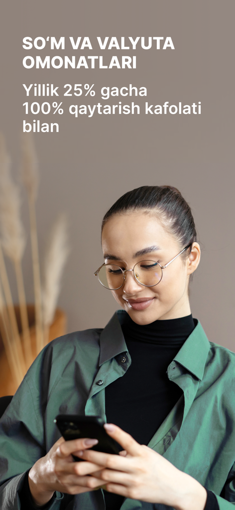 Young woman using Ipak Yuli Mobile app for currency deposits with high annual interest rates.