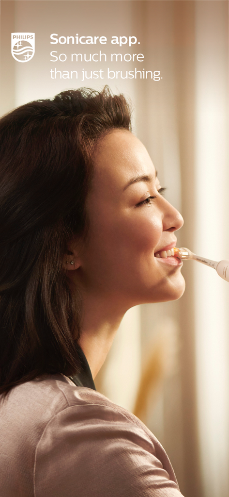 A woman smiling while brushing her teeth with a Philips Sonicare electric toothbrush