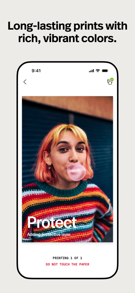 Polaroid Hi·Print - Una foto colorida de una mujer joven soplando una burbuja de chicle mostrada en la app Polaroid Hi-Print durante el proceso de impresión