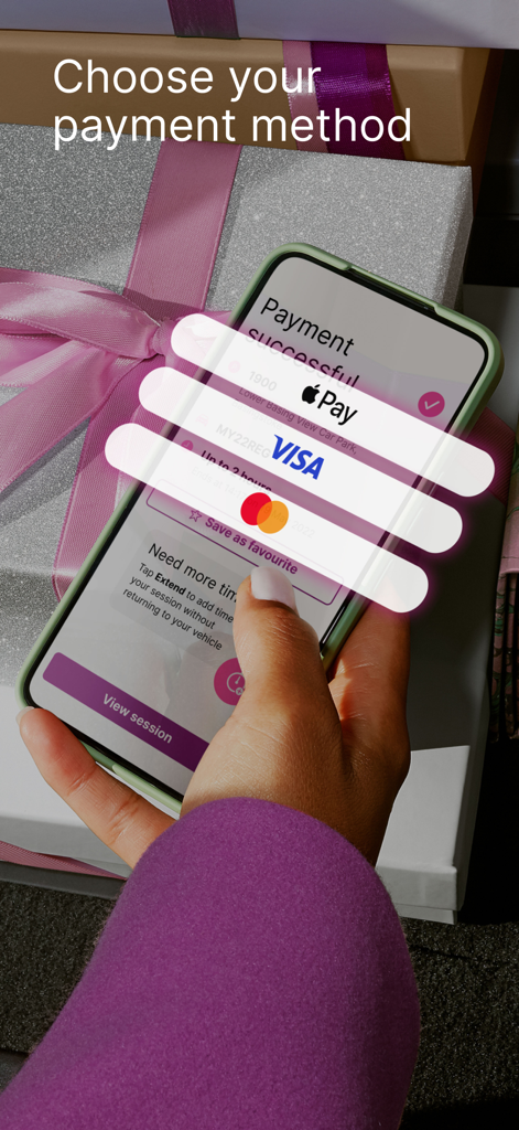 A hand holding a smartphone displaying payment methods like Apple Pay and credit cards within the RingGo parking app.
