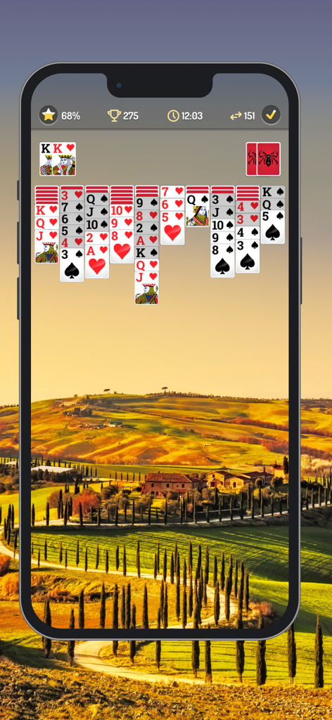 Interfaz del juego móvil de Spider Solitaire con fuentes de cartas grandes y un fondo de paisaje escénico.