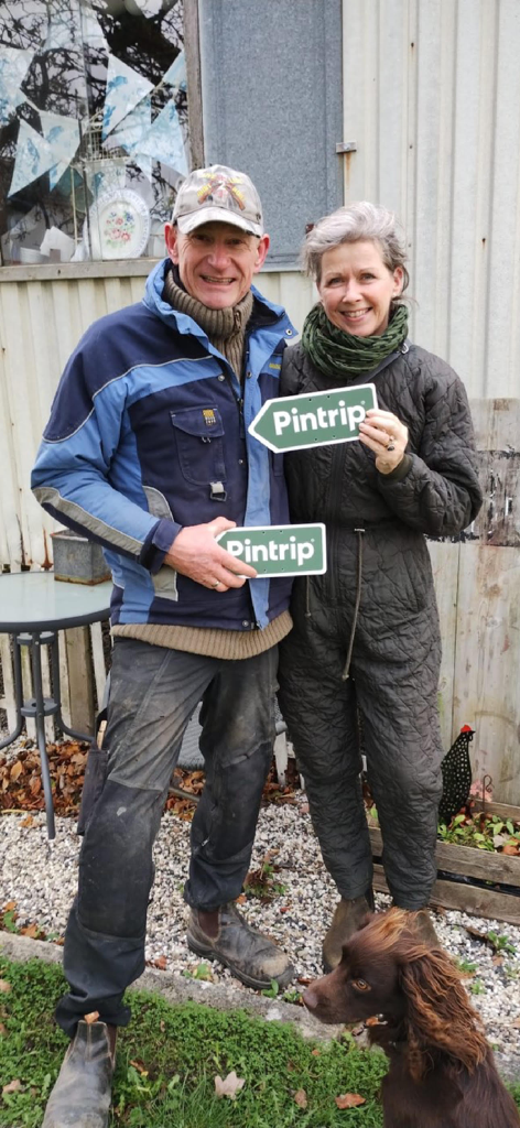 Pintrip - motorhome stopovers - A smiling couple holding Pintrip signs at a local Danish farm stopover