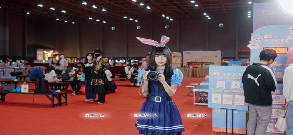 Love of Mobius - Uma jovem com um vestido azul e orelhas de coelho segurando uma câmera durante uma cena interativa de convenção em Love of Mobius