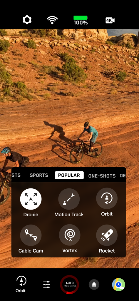 Skydio-App-Oberfläche mit kinoreifen Flugmodi wie Orbit und Dronie, während Mountainbiker in einer Wüste verfolgt werden.
