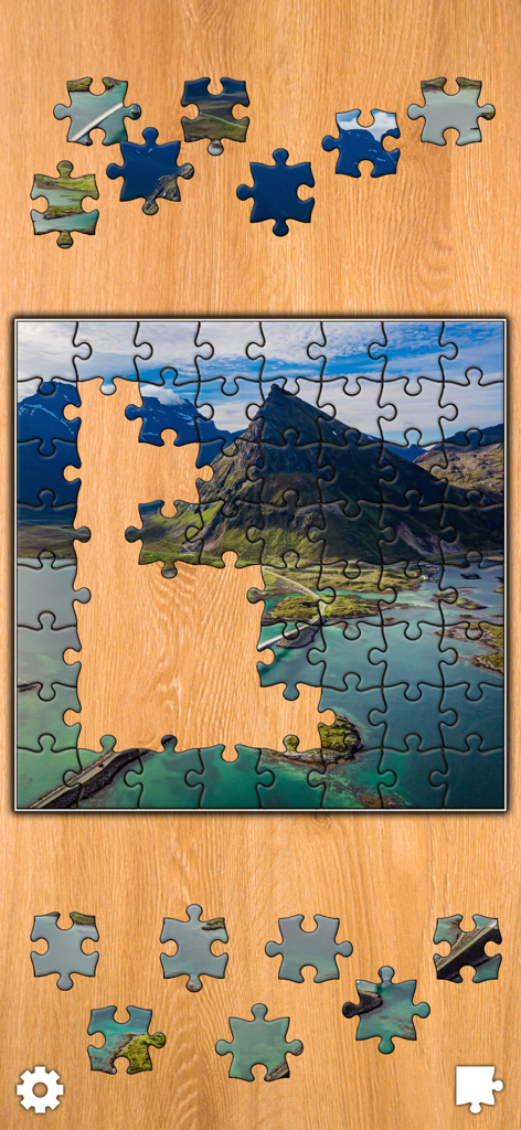 Captura de pantalla del juego de Jigsaw Puzzles Titan mostrando un rompecabezas de paisaje montañoso siendo ensamblado sobre un fondo de madera.