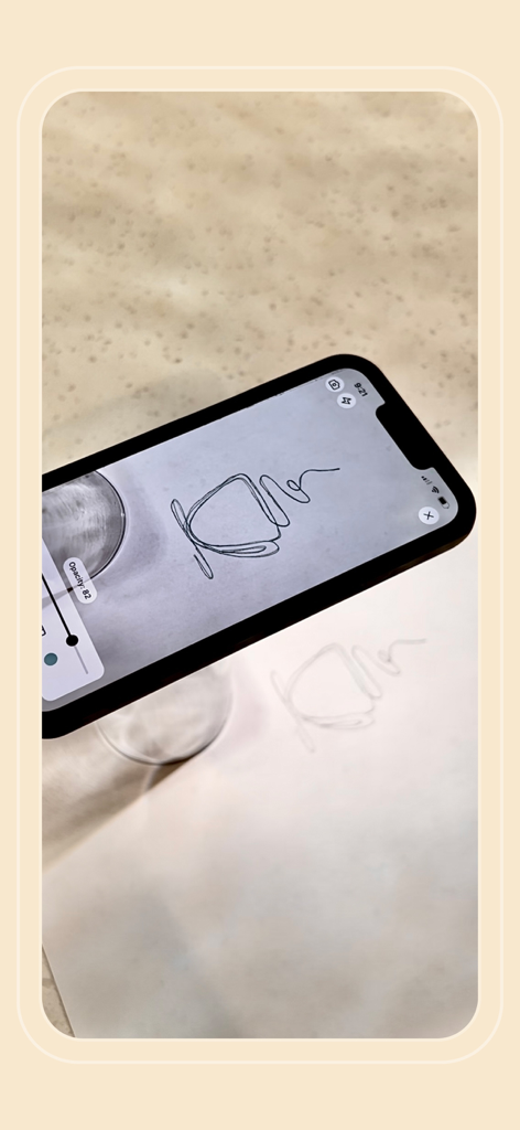 A smartphone using the Flowly AR app to trace a line drawing onto paper
