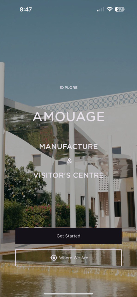 Amouage Visitors' Center - Welcome screen of the Amouage Manufacture and Visitor Center mobile app showing the entrance to the facility and navigation buttons.