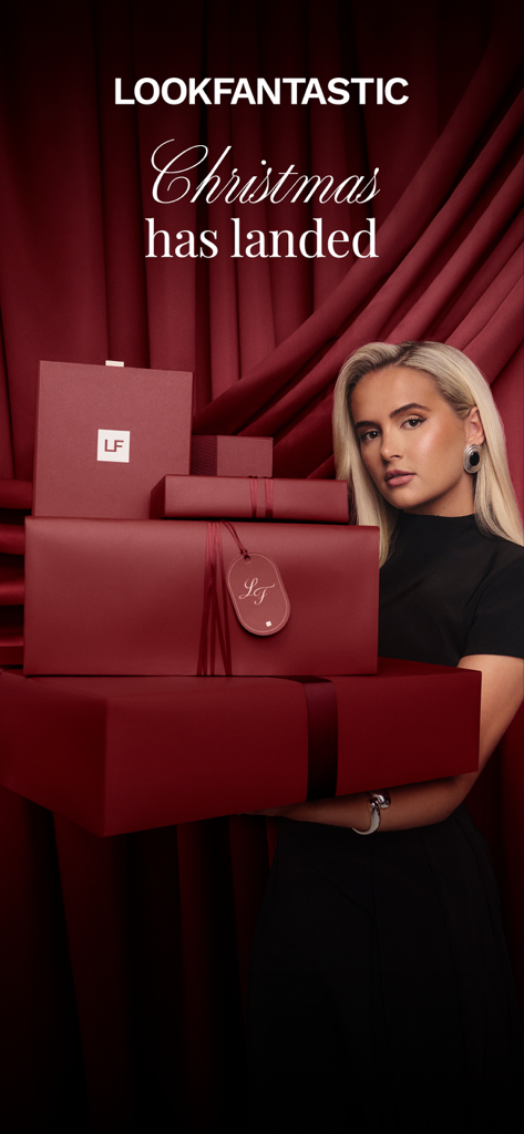 Molly-Mae Hagueが積み重ねられた赤いLOOKFANTASTIC高級クリスマスギフトボックスを手に持っている