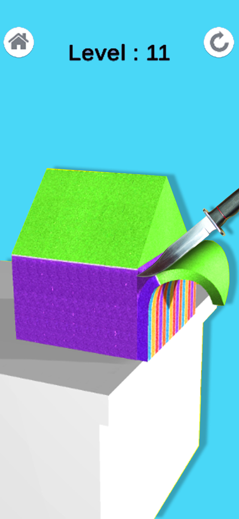 A knife slicing a green and purple house shaped block of kinetic sand to reveal rainbow layers inside