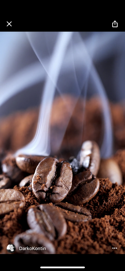 A professional cinemagraph featuring roasted coffee beans with rising steam and smoke