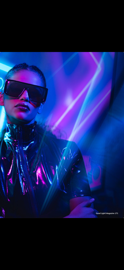 Un ritratto futuristico di una donna con un outfit nero lucido e occhiali da sole con illuminazione da studio vibrante blu neon e viola