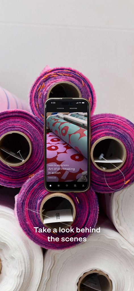 Marimekko | Fashion & Design - A smartphone displaying the Marimekko app backstage view featuring the art of printmaking surrounded by vibrant rolls of fabric.