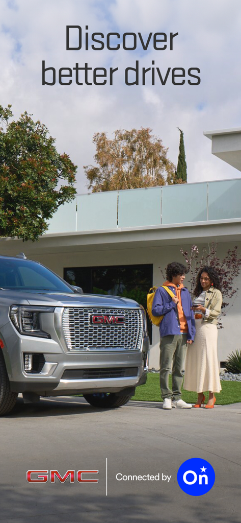 myGMC - A couple standing next to a GMC SUV looking at the myGMC mobile app on a smartphone in a suburban driveway.
