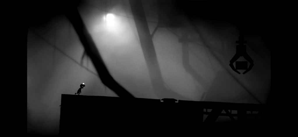 Playdead's LIMBO - Una captura de pantalla de juego en blanco y negro del LIMBO de Playdead que muestra a un niño silueteado corriendo a través de un entorno industrial oscuro y brumoso.