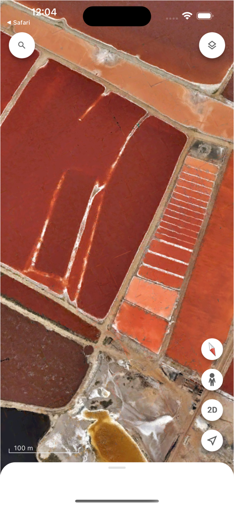 Satellite view of red and orange salt evaporation ponds in the Google Earth mobile app