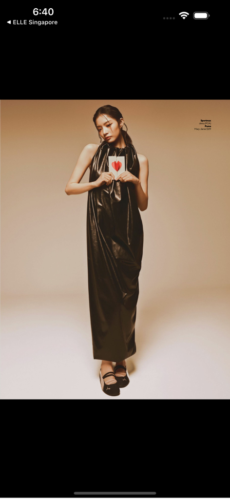 Fashion model wearing a long black halter dress and holding a card with a heart