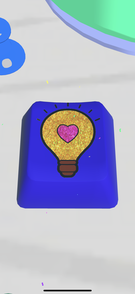 A blue keyboard keycap decorated with a gold glitter lightbulb and a pink heart