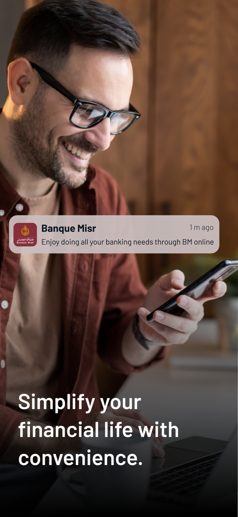 BM Online - Ein lächelnder Mann, der eine Benachrichtigung der Banque Misr-App auf seinem Smartphone betrachtet, mit dem Text Vereinfachen Sie Ihr Finanzleben mit Komfort.
