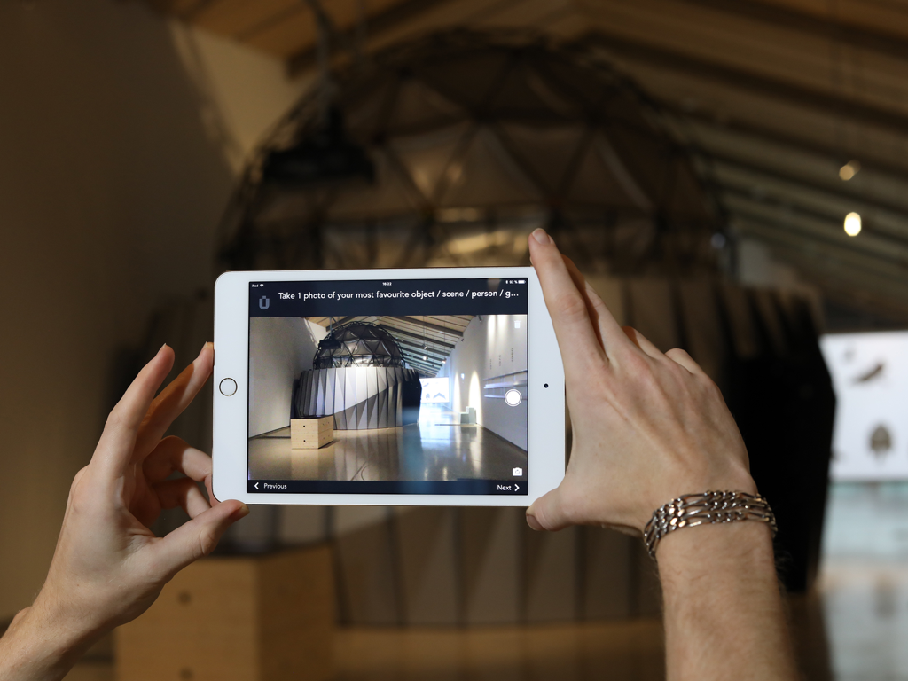 A person using the Muse app on an iPad to photograph a museum exhibit as part of a visitor survey.