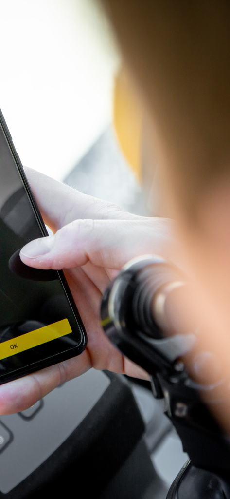 MyAssistant for Earthmoving - Un operador de maquinaria pesada usa la app Liebherr MyAssistant para Movimiento de Tierras en un smartphone dentro de la cabina de una excavadora.