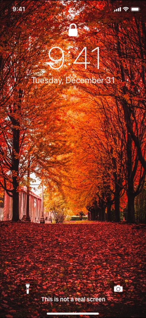 iPhone lock screen featuring a vibrant autumn forest wallpaper with red and orange leaves