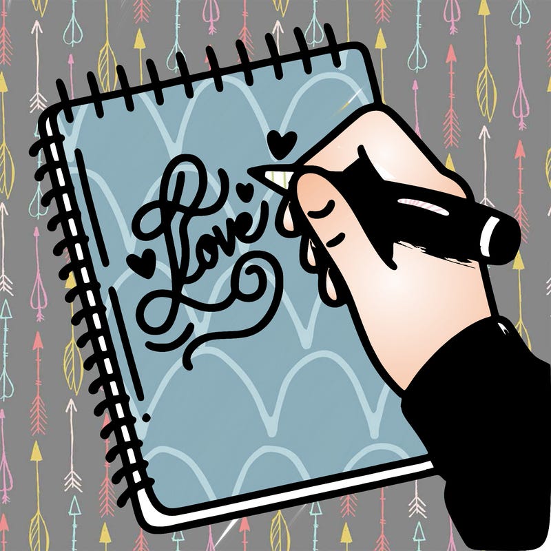 a hand writing “love” in calligraphy on a notebook