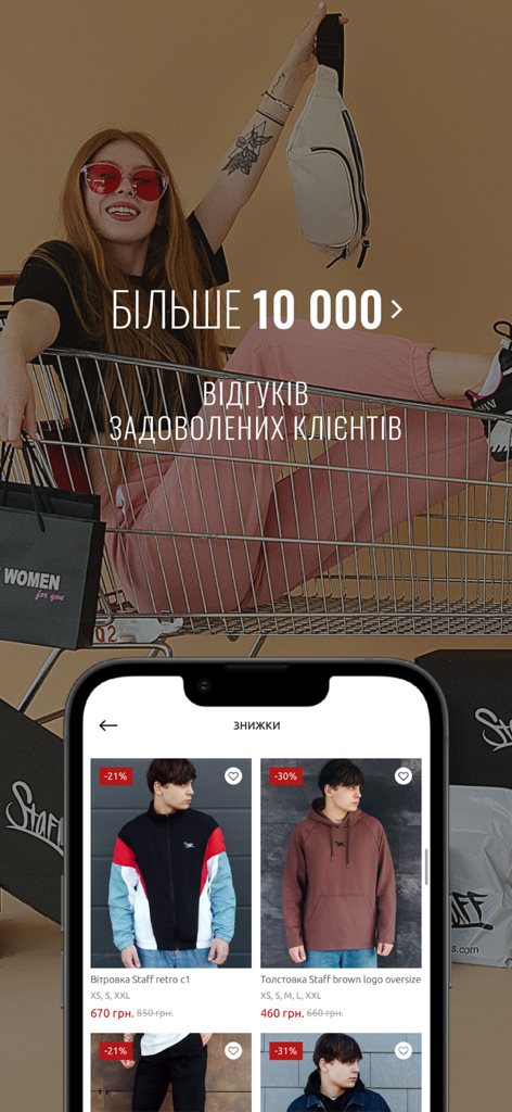 Una mujer sentada en un carrito de compras sobre una pantalla de smartphone que muestra streetwear con descuento en la app Staff Clothes.