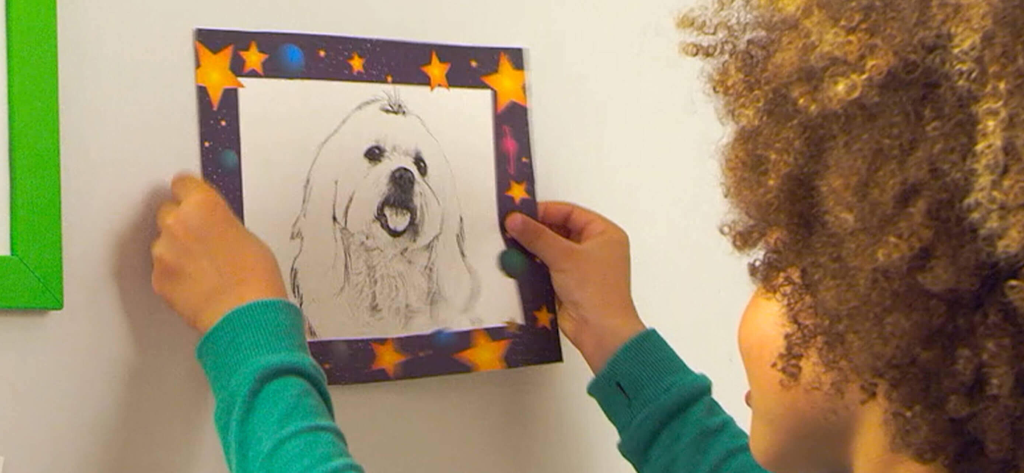 A child holding a finished pencil sketch of a dog