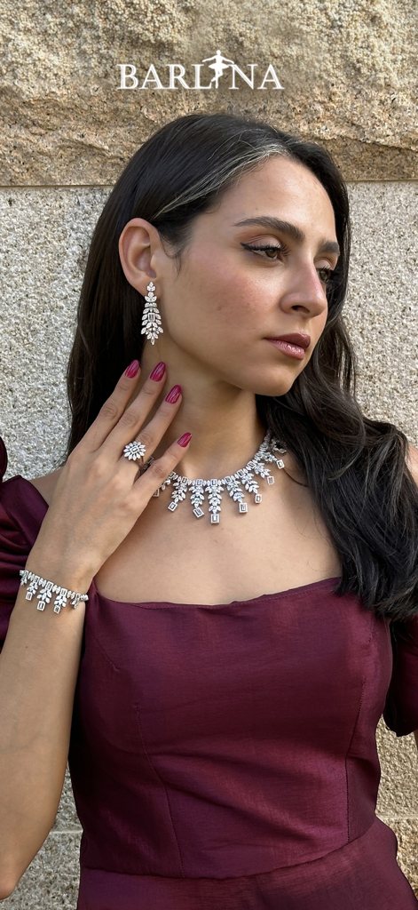 A woman wearing an elegant maroon evening dress and silver jewelry set from the Barlina app.
