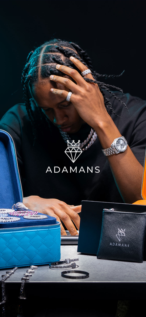 Um homem usando joias iced out, incluindo um relógio e anéis, enquanto navega em uma coleção de joias Adamans