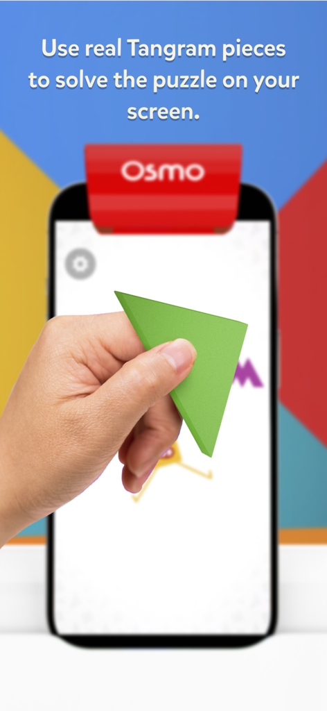 Osmo Tangram - A hand holding a green physical tangram piece to solve a puzzle on an iPhone screen using Osmo technology