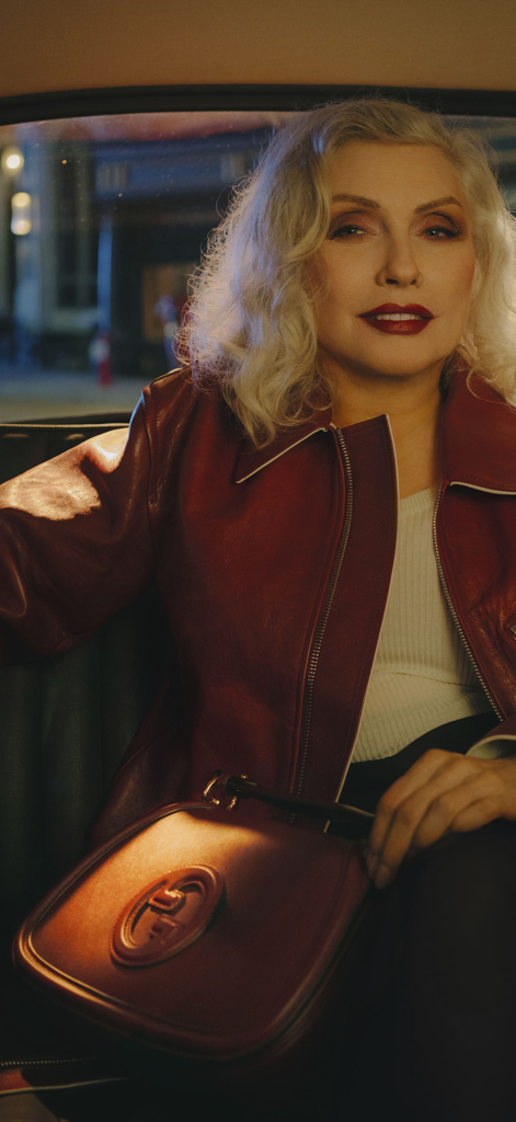 GUCCI - Woman wearing a red leather jacket and holding a Gucci handbag in a car