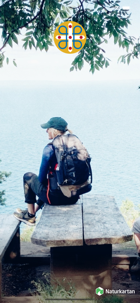 Wanderin mit Rucksack ruht sich auf einer Holzbank mit Blick auf einen großen See in Schweden aus