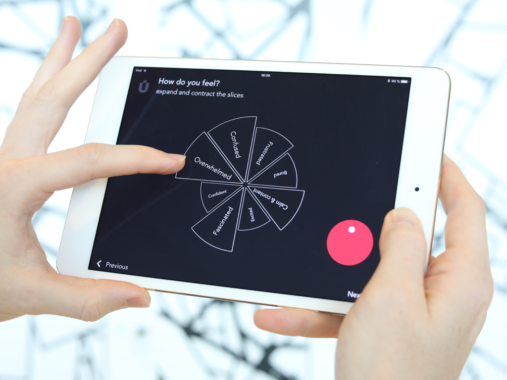 A person using the Muse app on a tablet to provide feedback through an interactive emotional sentiment wheel.