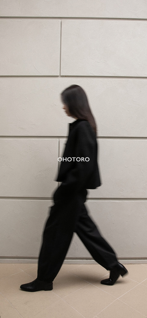 OHOTORO - Una mujer paseando con un atuendo negro minimalista que muestra la moda de OHOTORO