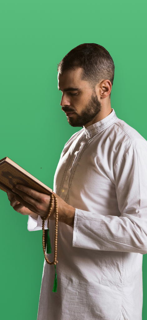 Un homme en tenue traditionnelle blanche lisant le Coran et tenant des perles de prière sur fond vert