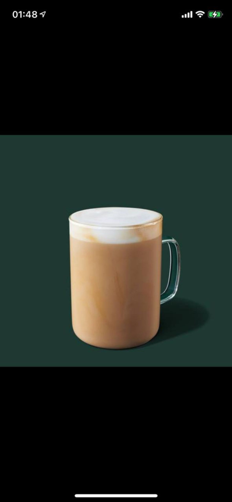 foamy latte coffee in a glass mug on a dark green background