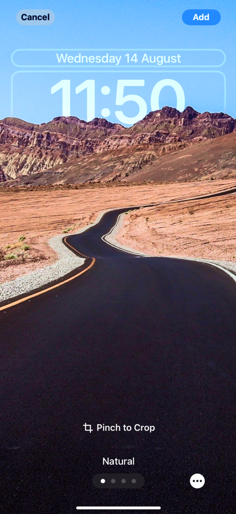 A preview of a winding desert road wallpaper on an iPhone lock screen with time and date display