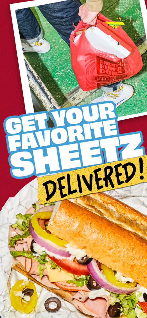 A person holding a Sheetz delivery bag above a large sub sandwich with fresh toppings
