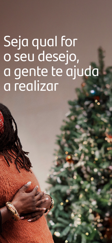 Banco Santander Brasil - Una mujer con un suéter naranja parada cerca de un árbol de Navidad con un mensaje motivacional de Santander Brasil