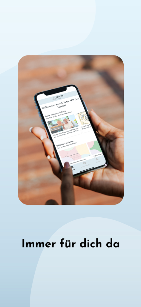 FEMNA Care - A person holding a smartphone displaying the FEMNA Care app dashboard with health lessons and personalized recommendations