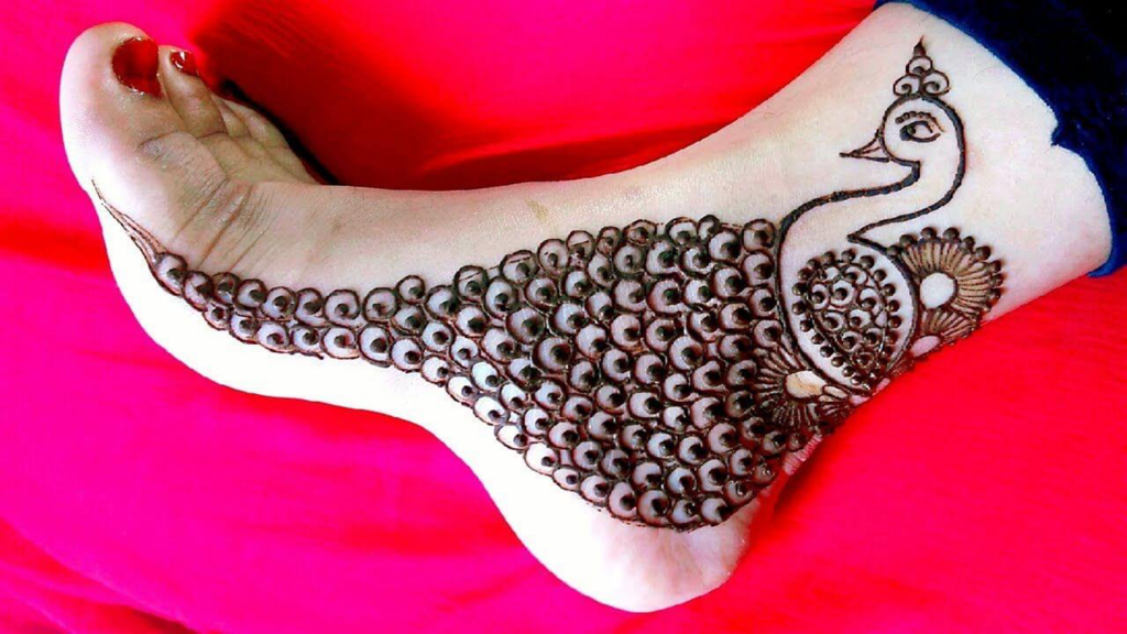 A detailed peacock henna design applied to the side and top of a woman's foot.