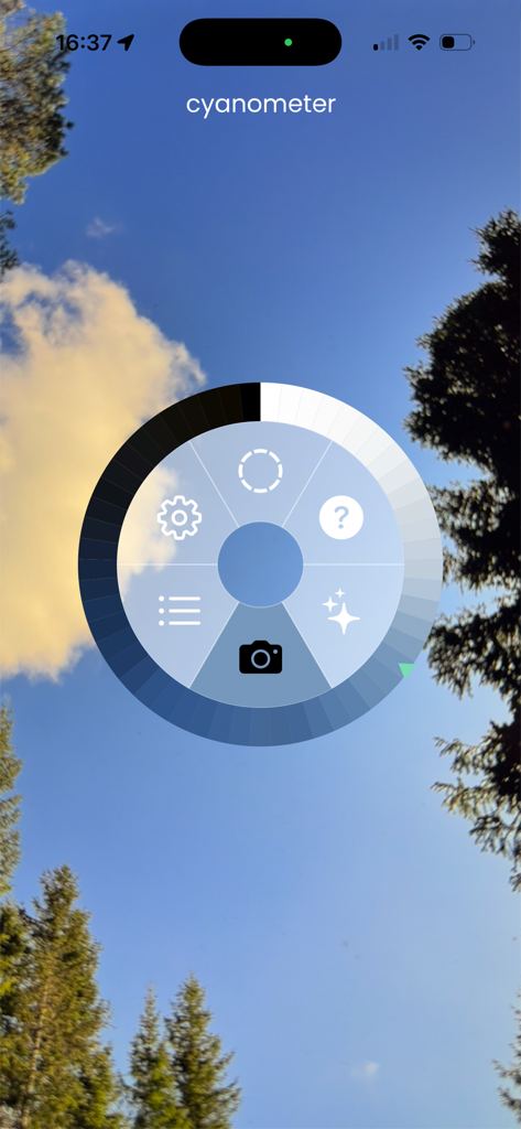Cyanometer - Cyanometerアプリのインターフェース。木々のある澄んだ青い空の上に円形のカラースケールが表示されています。