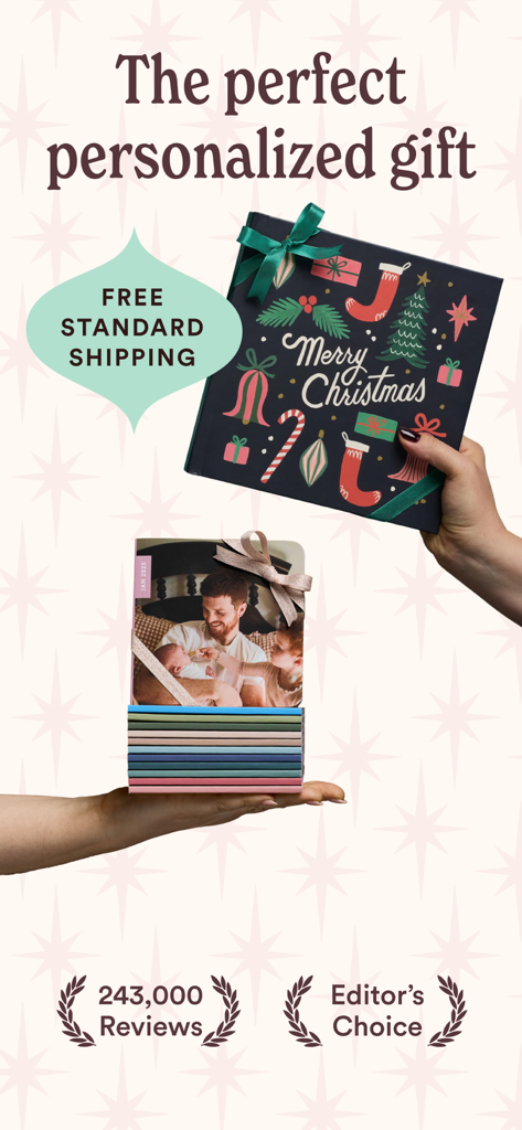 Mãos segurando um álbum de fotos personalizado com tema de Natal e uma pilha de álbuns familiares coloridos e personalizados