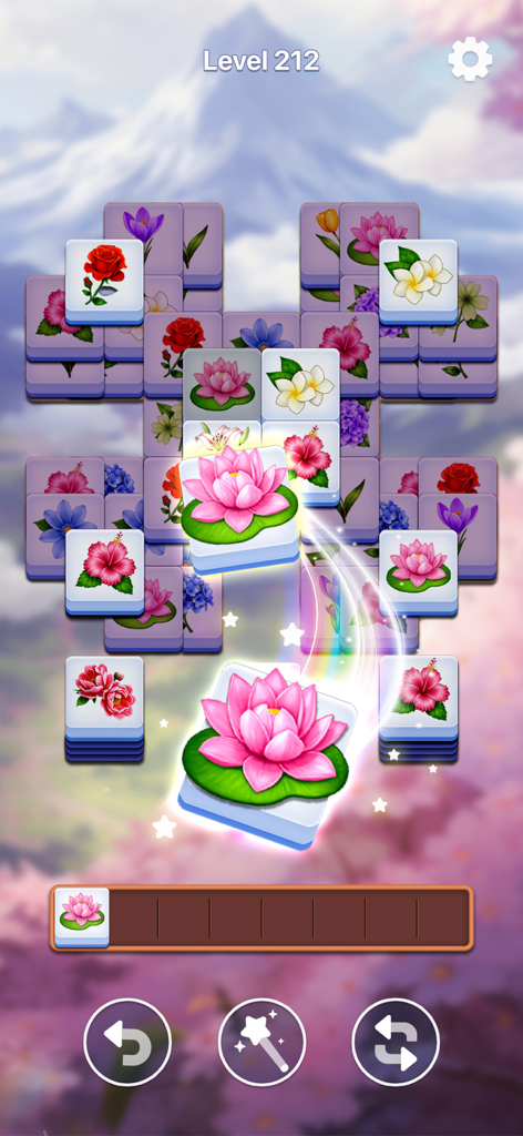 A floral tile matching game screen showing various flower tiles and a serene mountain background.
