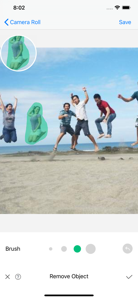 iPhone screenshot showing a person being selected with a brush tool for removal from a beach photo