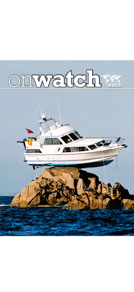 Un yate blanco posado sobre una gran formación rocosa en el océano de la revista Boating