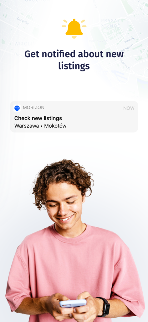 Un joven sonriendo mientras mira una notificación push de nuevos listados de bienes raíces en la aplicación Morizon