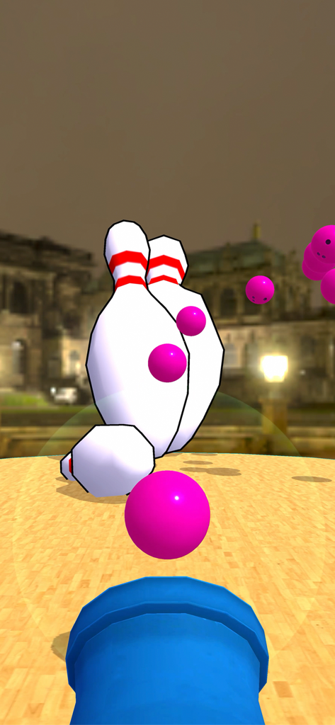 Eine blaue Kanone feuert pinke Bowlingbälle auf Pins in einer städtischen Umgebung bei Nacht.