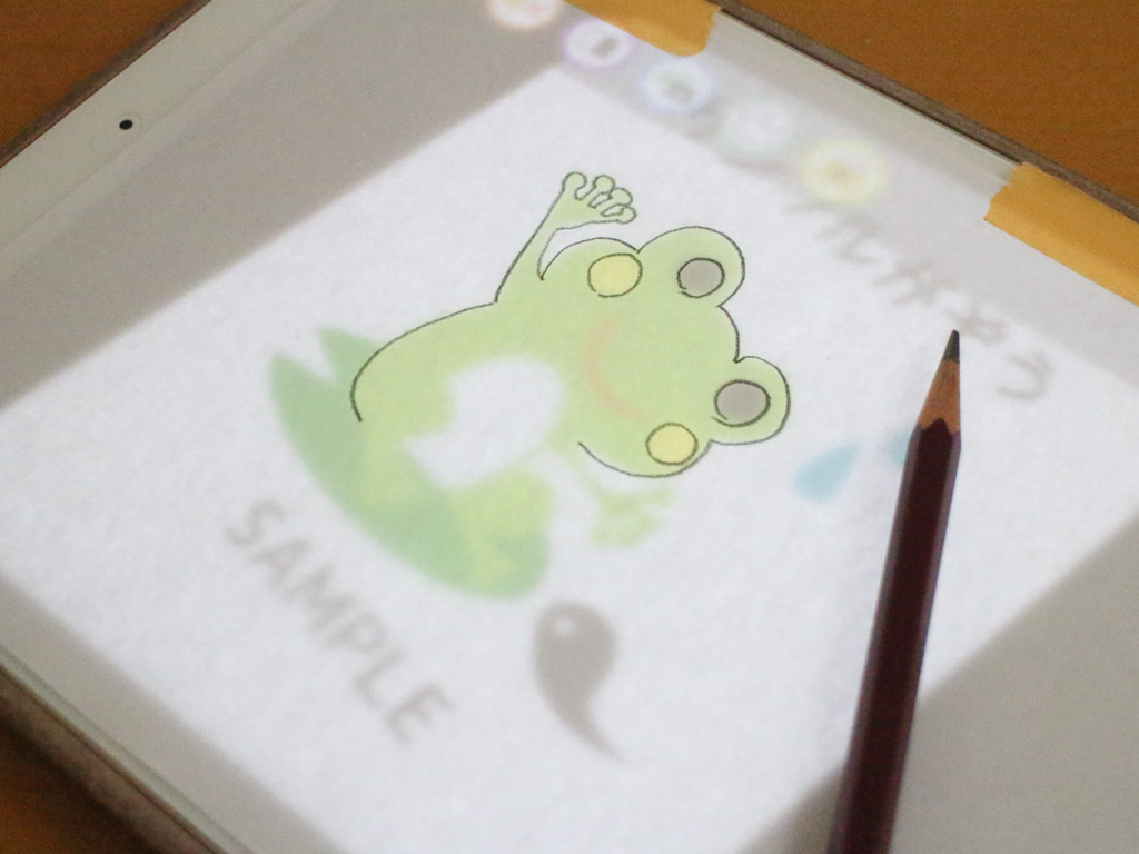 Trace illustration - Un crayon à côté d'une illustration de grenouille sur papier en train d'être décalquée depuis un écran d'iPad
